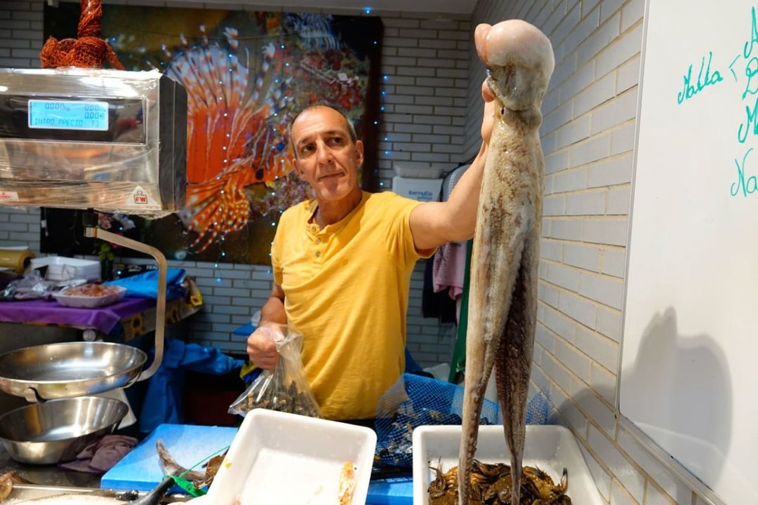 Un vendedor muestra uno de los pulpos que se venden en el mercado.