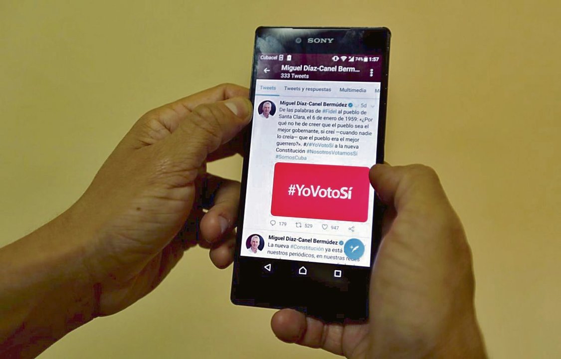 Un hombre muestra la pantalla de su móvil con un hashtag relativo a política.