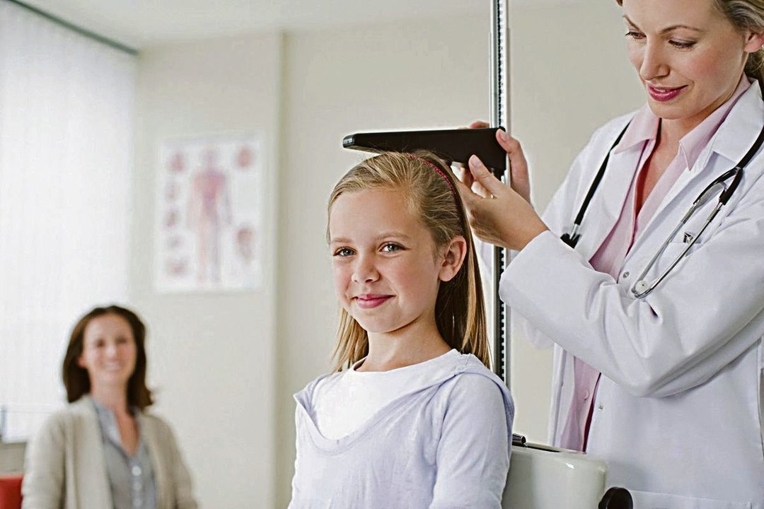 Una médica mide la estatura de una niña.