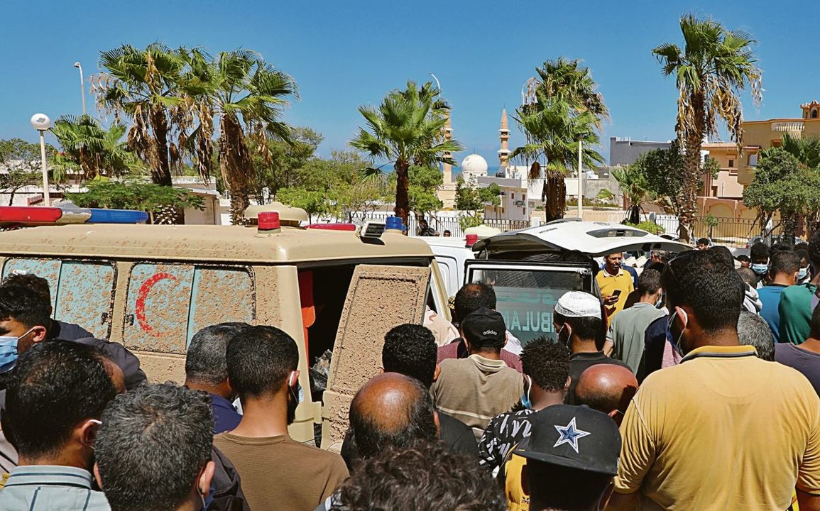 Los habitantes esperan mientras los restos de las víctimas son llevados al hospital de Derna.