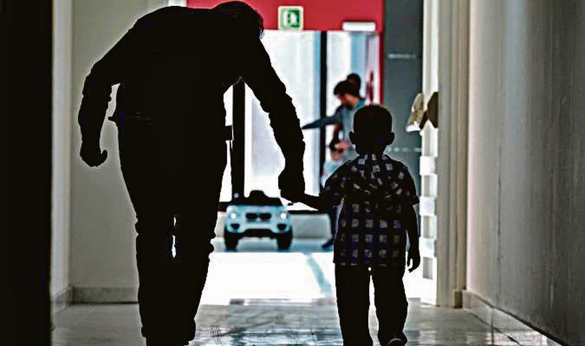 Un hombre acompaña a un niño por los pasillos de un hospital.