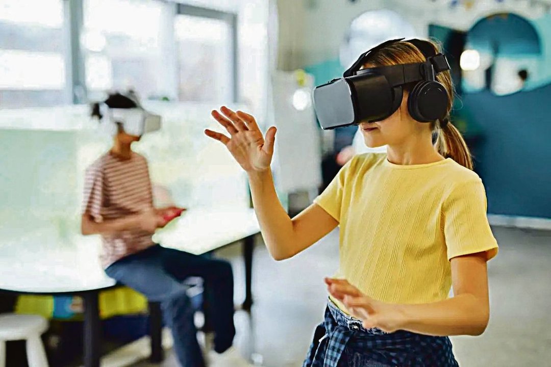 Dos escolares prueban gafas de realidad virtual.