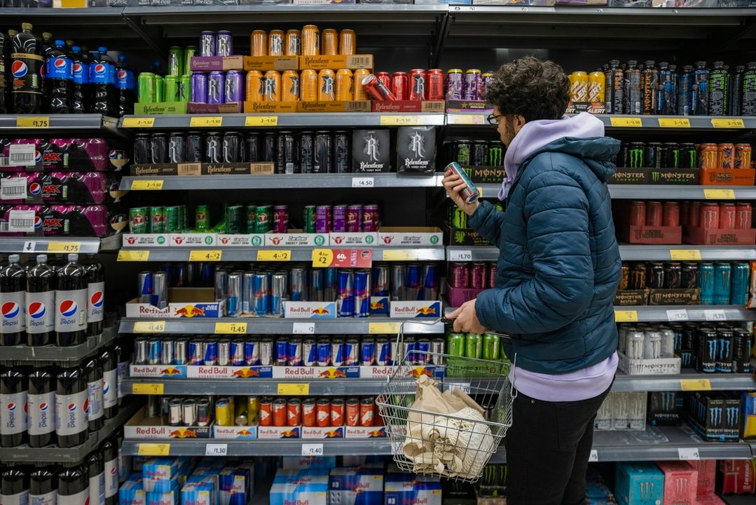 Un joven mira la sección de bebidas energéticas en el supermercado. // Europa press