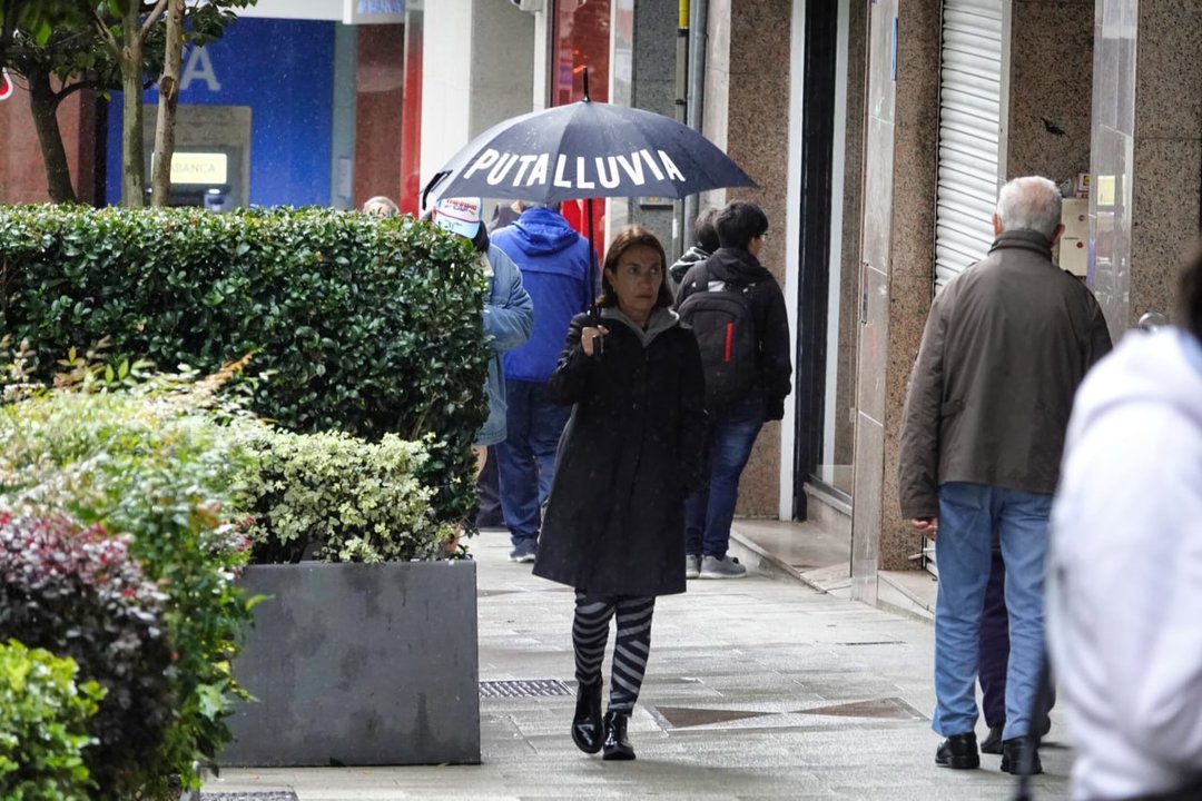 Una mujer lleva un paraguas en Vigo con el escrito "Puta lluvia". // Vicente Alonso