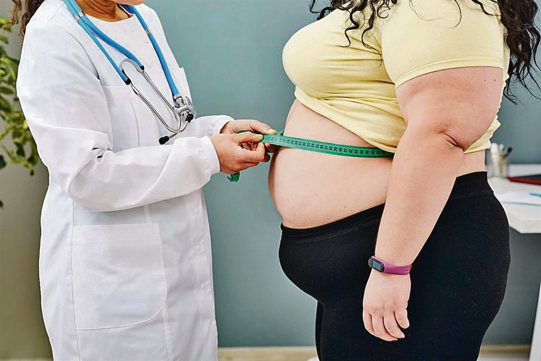 Una médico tratando en su consulta a una paciente que sufre obesidad.