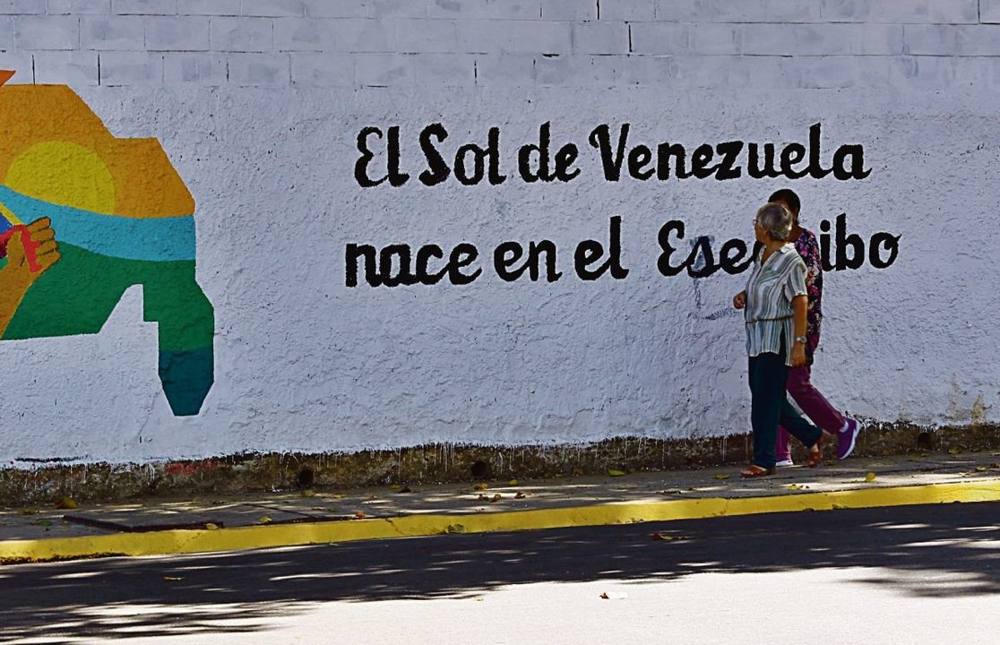 Una pareja pasea delante de una pintada reclamando para Venezuela el Esequibo.