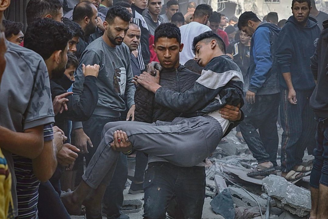 Un joven palestino herido es llevado en brazos por otro joven tras un bombardeo israelí.