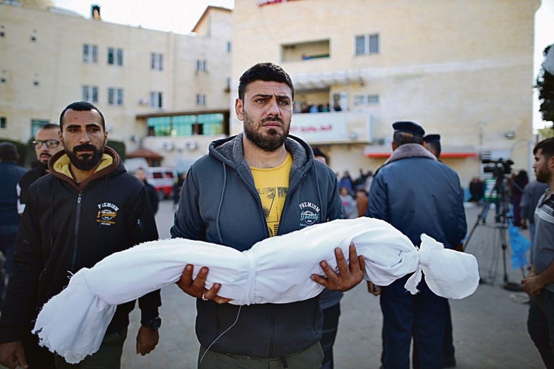 Un hombre sostiene el cuerpo de una víctima en Gaza.