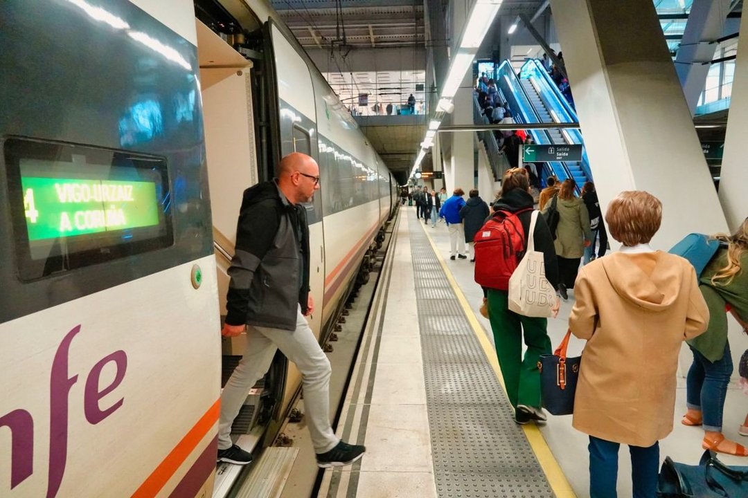 Un pasajero se baja del tren que conecta A Coruña con Vigo en la estación de Urzaiz, junto a otros pasajeros.