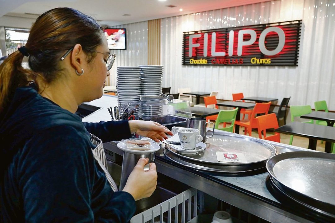 Una camarera se dispone a servir un café con leche en la cafetería Filipo.