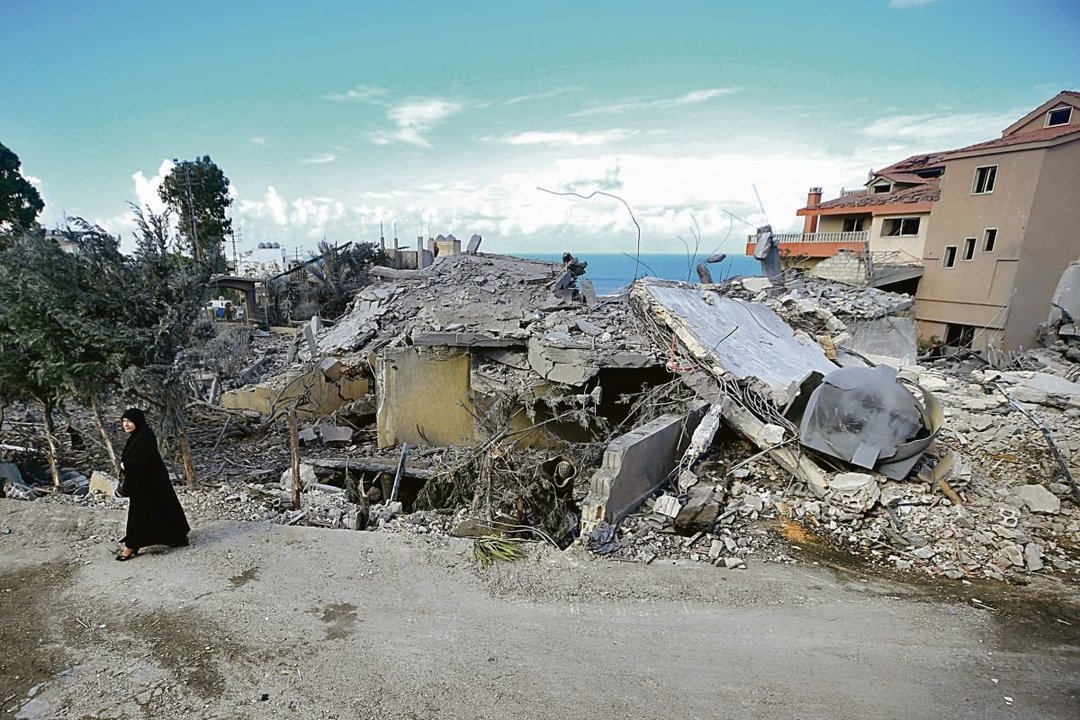 Una mujer pasa frente a edificios destruidos por Israel en Naqura, al sur de Líbano