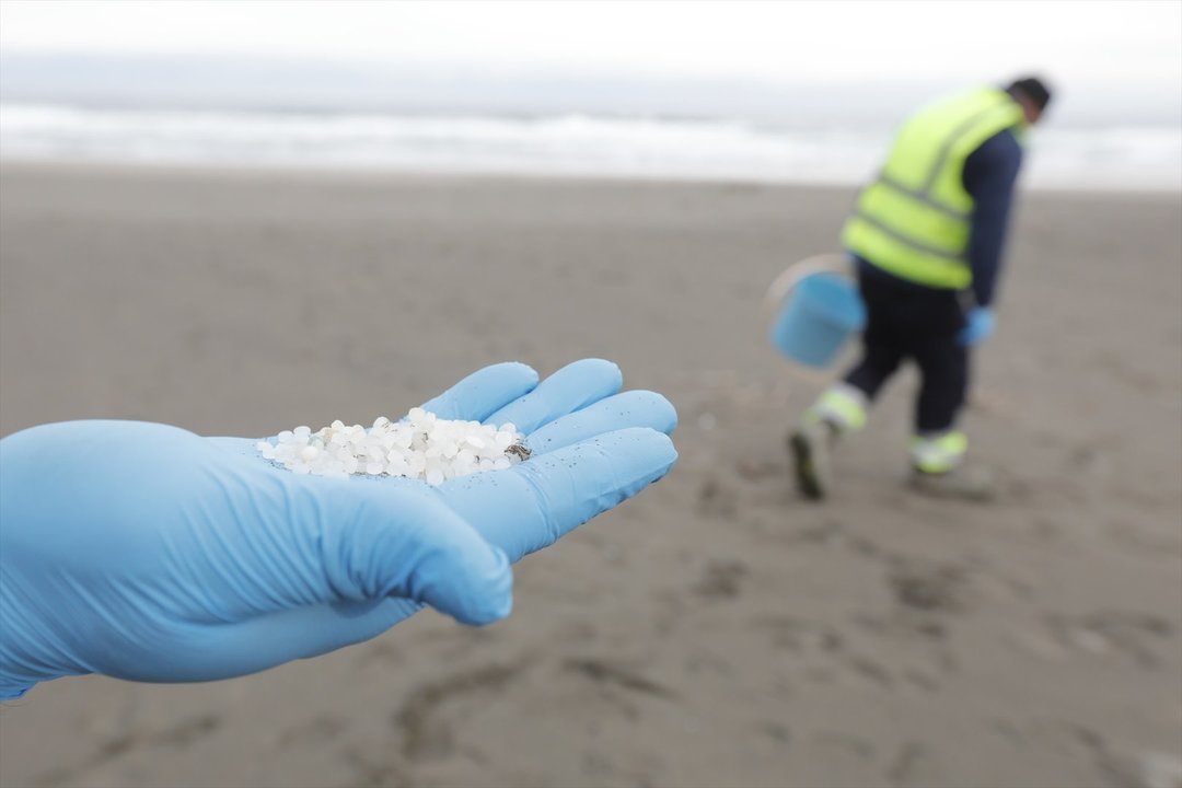 Un operario de TRAGSA coge con la mano pellets de plástico, en la playa Otur, a 9 de enero de 2024, en Valdés, Asturias. // EP