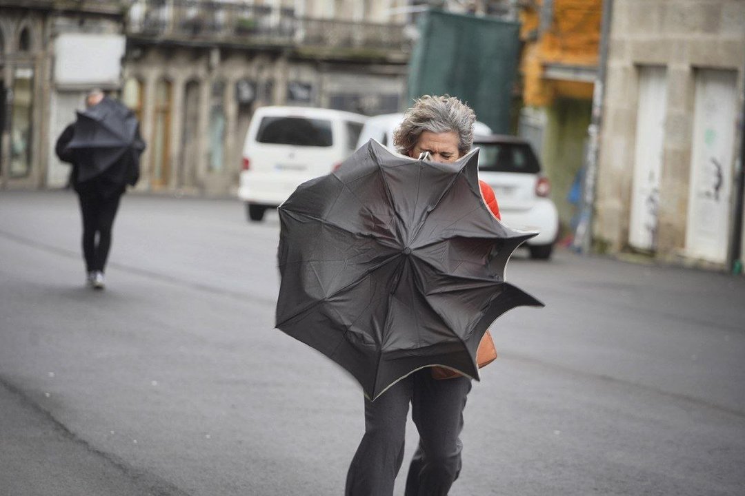 La lucha de una persona en Vigo con el viento al intentar cubrirse con un paraguas.