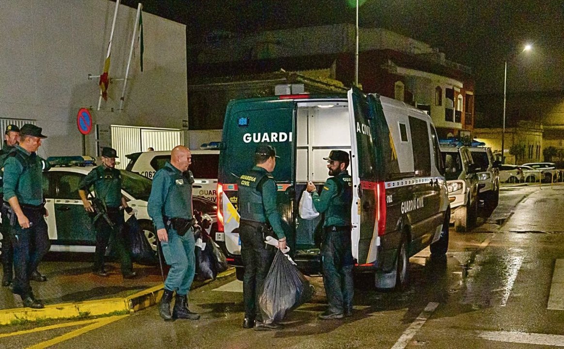 Guardias civiles suben a un furgón pertenencias de los detenidos.