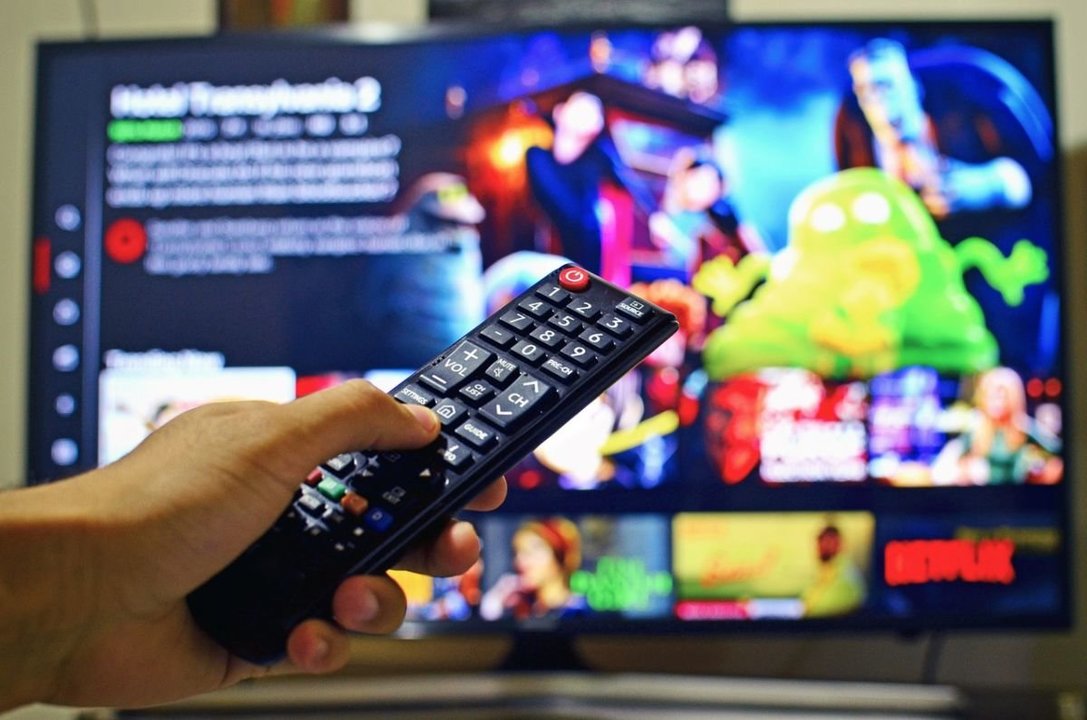 Una persona enciende el televisor y accede a una plataforma de contenido audiovisual de pago.