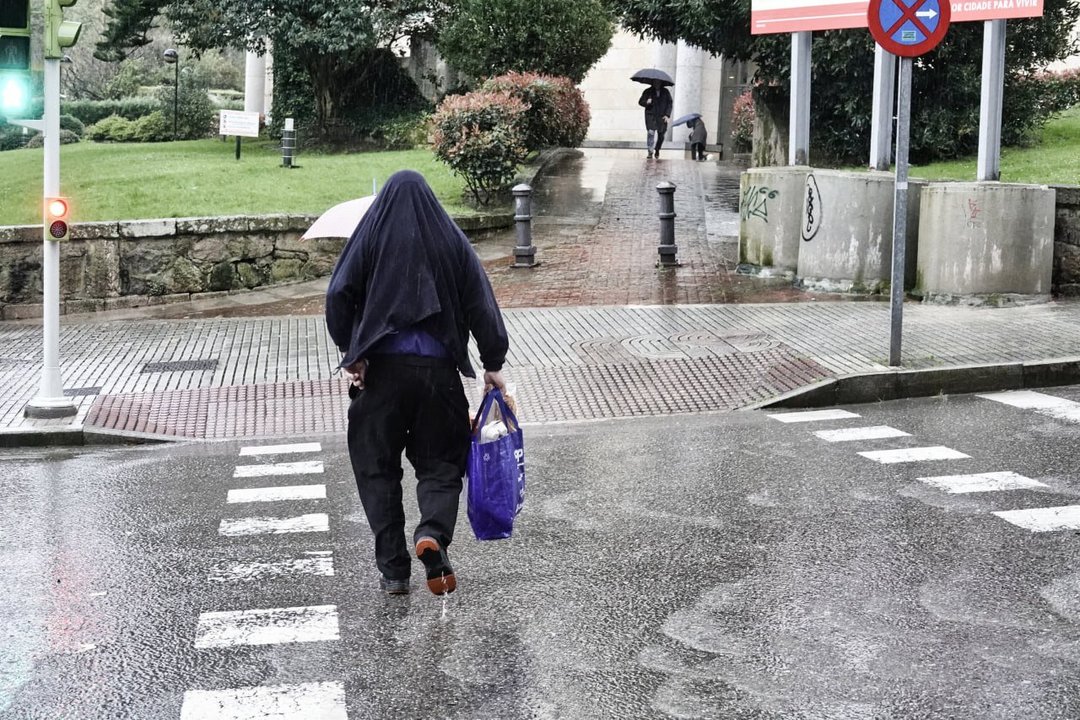 Una persona camina bajo la lluvia sin paraguas. // Vicente Alonso