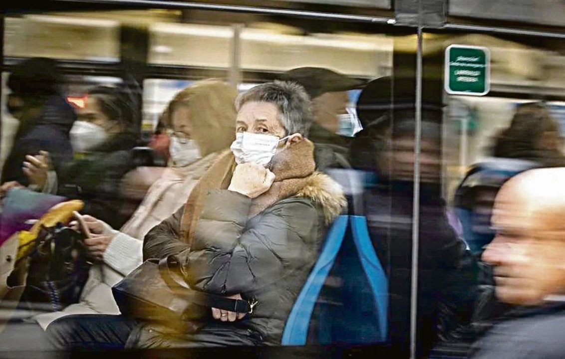 Grupos de viajeros con mascarilla en un transporte público.