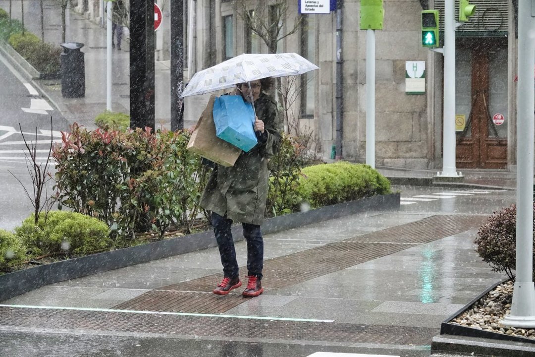 Una mujer hace frente a la lluvia y el viento en Vigo cargando con bolsas y el paraguas. // Vicente Alonso
