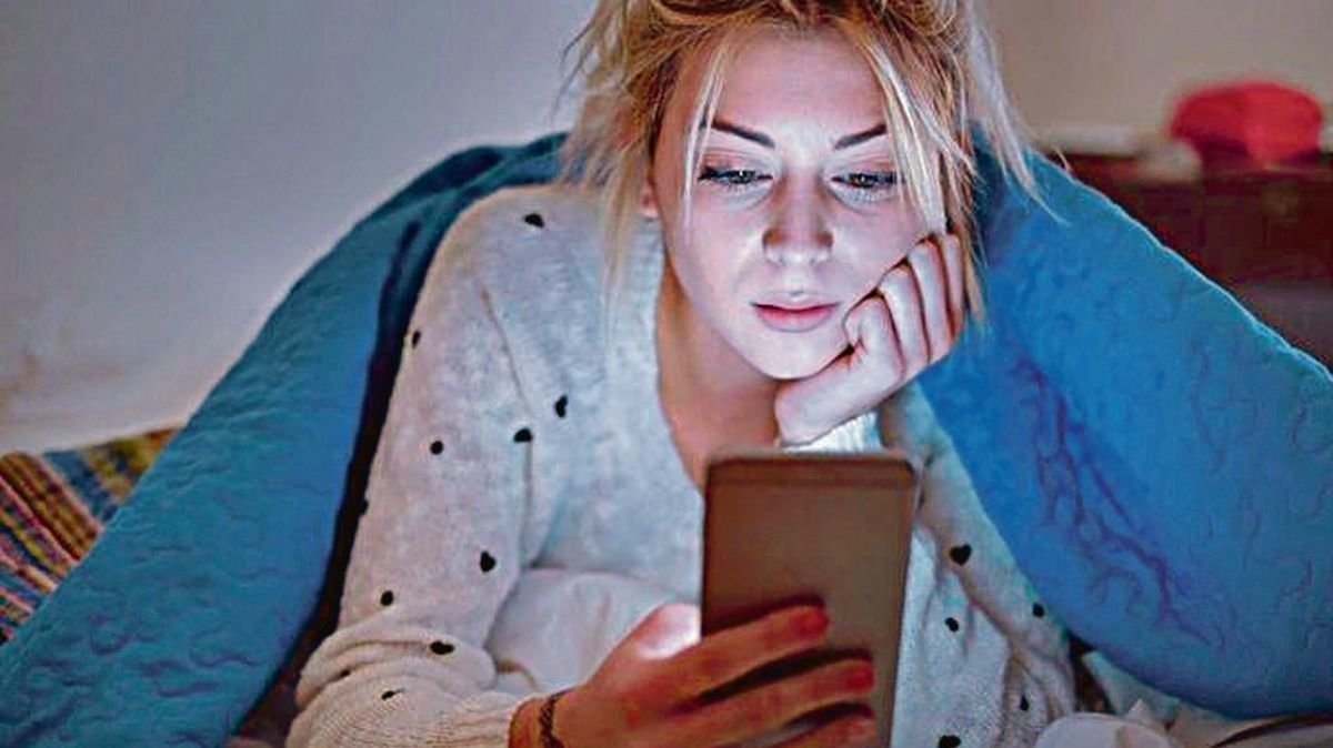 Una joven utiliza su teléfono antes de dormir.
