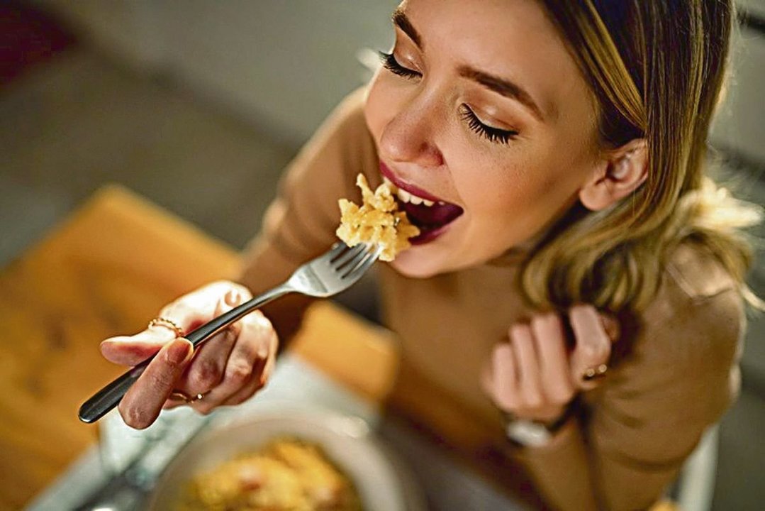 Una mujer comiendo un plato de pasta.