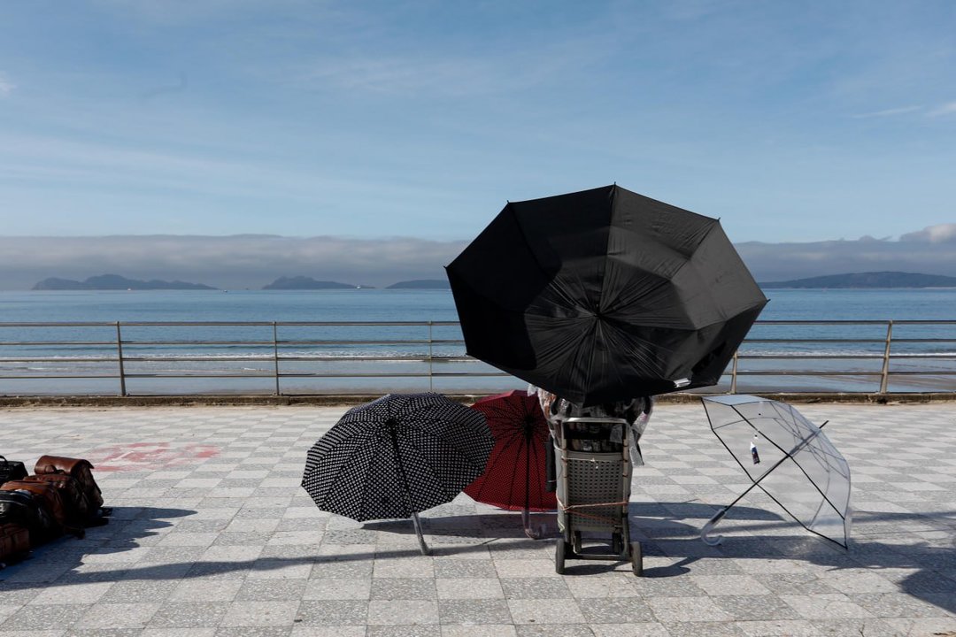 Un vendedor de paraguas con varios modelos en una jornada de buen tiempo en Vigo. // Jorge Santomé