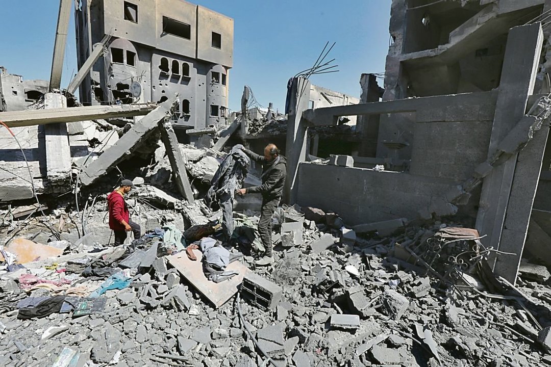 Dos palestinos buscan entre las ruinas enseres y comida para sobrevivir.