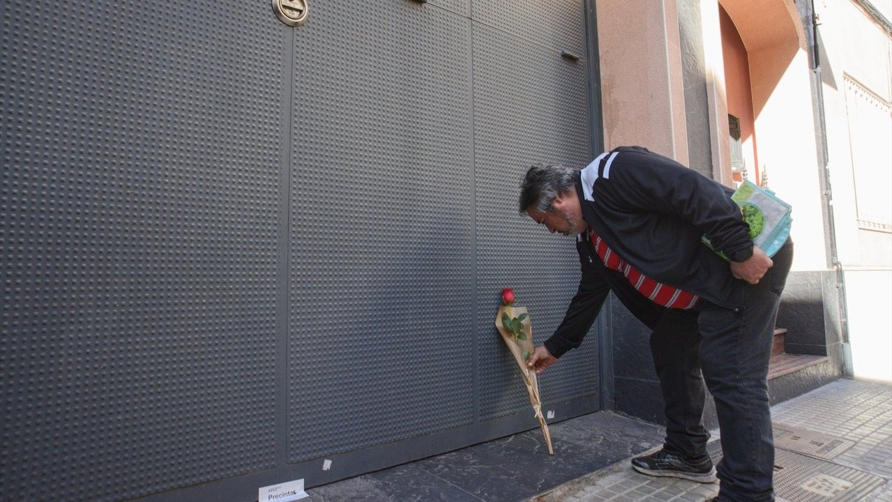 Un hombre deposita una rosa en el garaje de la vivienda donde un hombre ha matado presuntamente a su mujer y sus dos hijos menores. // E.P.