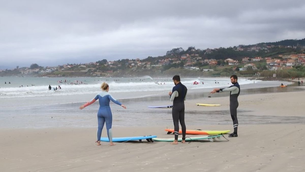 Surfistas calentando para meterse al agua y surfear olas.