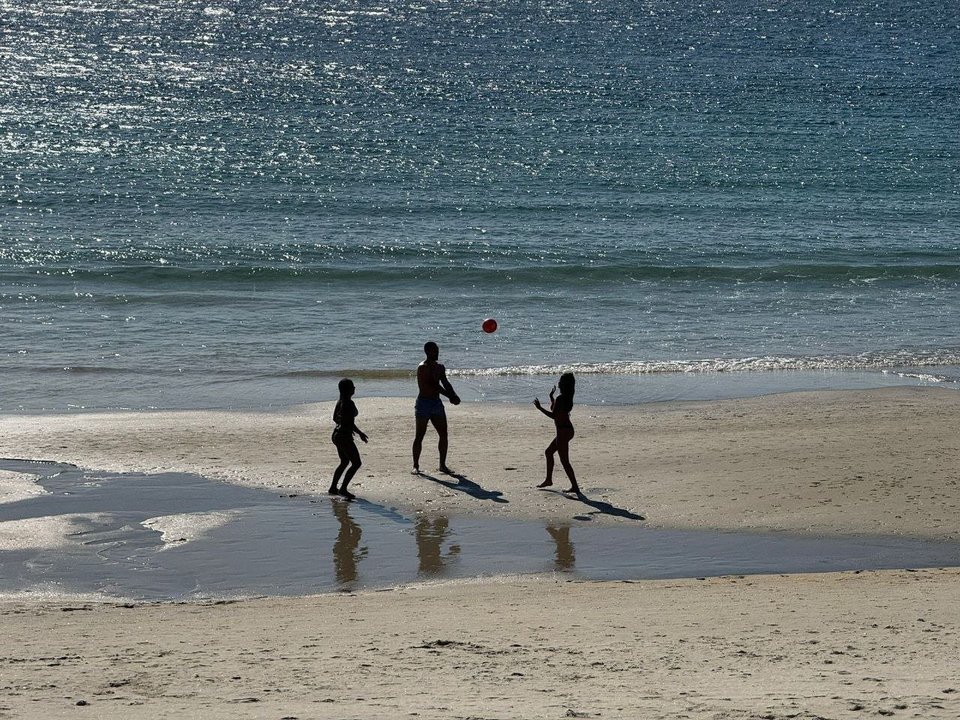 Tres personas juegan en la playa aprovechando el sol y calor en Vigo. // Alberte
