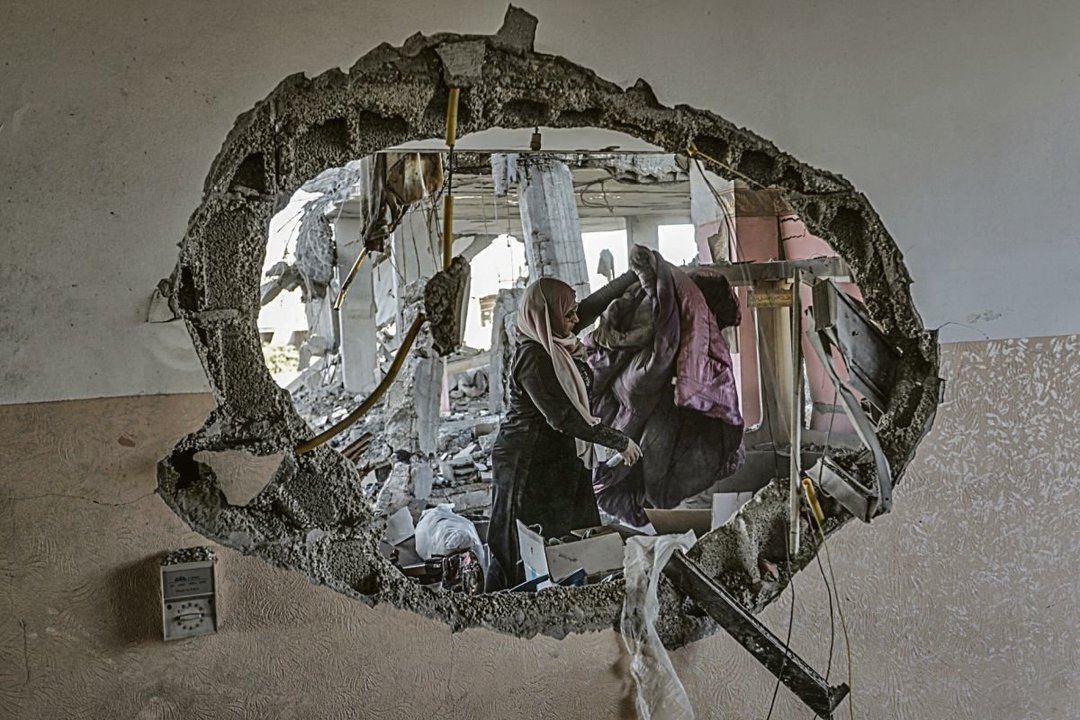Una mujer recoge ropa entre los escombros en Rafá.