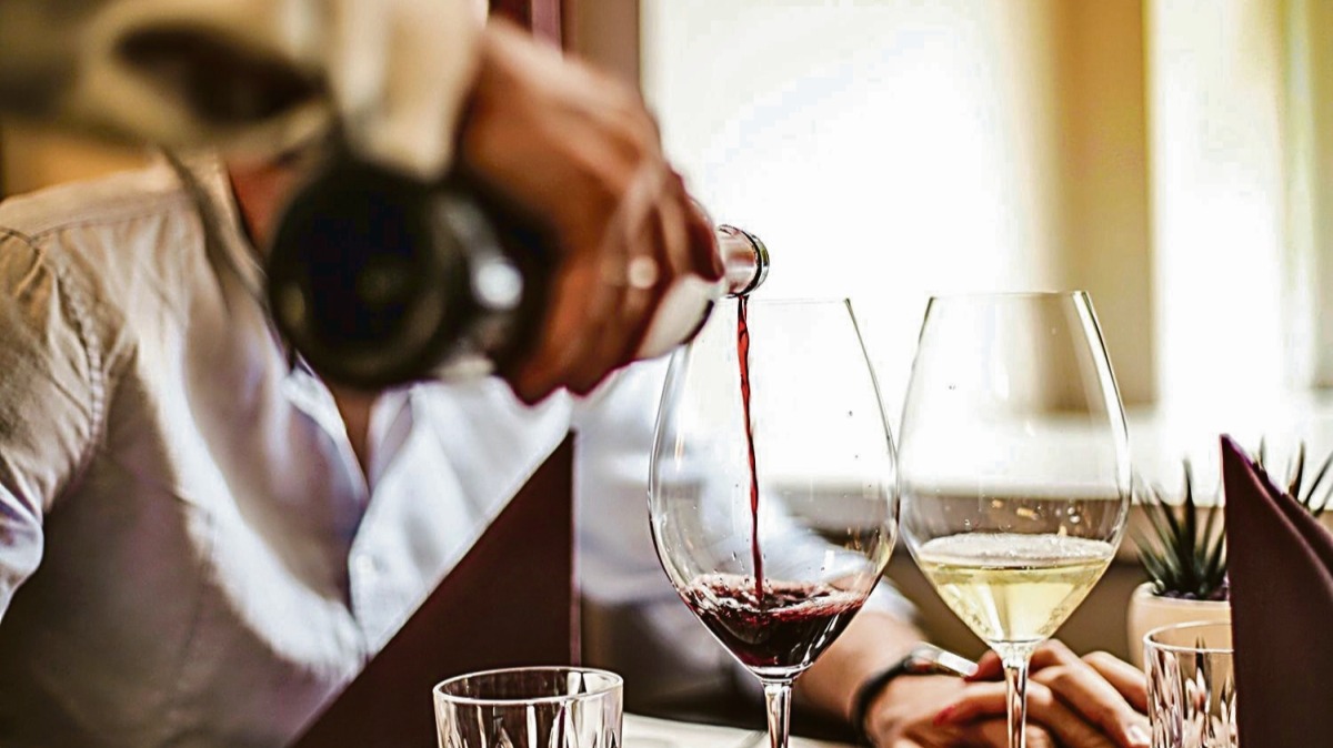 Un camarero de un restaurante sirve una copa de vino a un cliente.