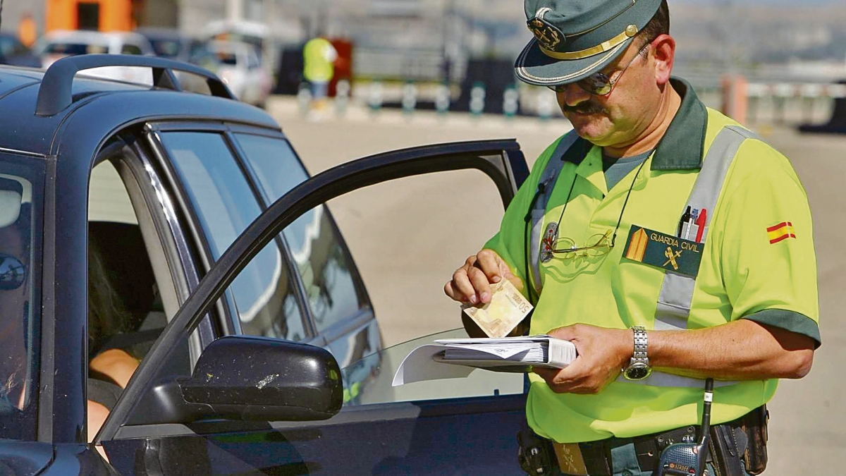 Un agente cobra una sanción de tráfico a un conductor.