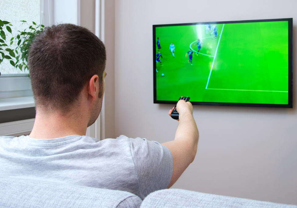 Una persona ve un partido de fútbol en un televisor.